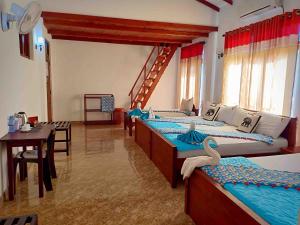 锡吉里亚Hungry Lion Resort的带三张床和一张桌子的房间以及用餐室