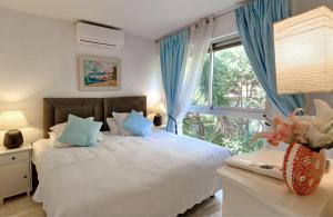 戛纳Villa Picaud - 50M plage, terrasse, clim - Unique Centre Cannes的一间卧室配有一张带蓝色窗帘的床和一扇窗户