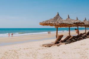美奈翠竹村庄海滩水疗度假酒店的海滩上的一组躺椅和遮阳伞
