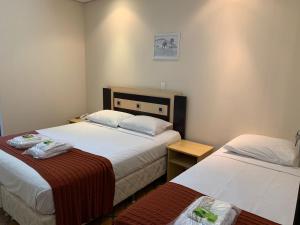LapaHotel Tropeiro da Lapa的酒店客房设有两张床和一张桌子。