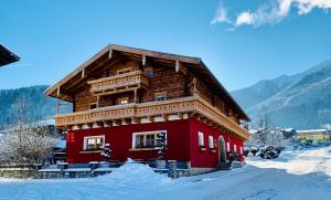 卡普伦APARTMENT SONNBLICK Kaprun Salzburg - incl Zell am See-Kaprun Summercard的雪上带木屋顶的红色建筑