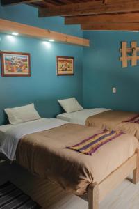 奥兰太坦波Doña Catta Casa Boutique的蓝色墙壁客房的两张床