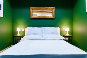 佩奥拉Monreal Boutique Townhouse - R024RM5的一间绿色卧室,配有白色的床和镜子