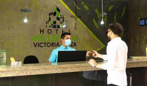 库库塔Hotel Victoria Plaza Millenium的两个人站在柜台上,戴着面具的人