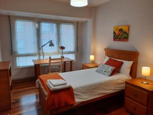 波图加莱特Apartamento Portugalete Gran Bilbao 3 dormitorios - 3 bedrooms的一间卧室配有一张床、一张书桌和一个窗户。