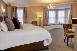 劳斯Best Western Plus Kenwick Park Hotel的卧室配有一张白色大床和一把椅子