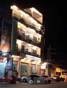 MingoraFR Darya E Swat Hotel的夜间停在大楼前的汽车