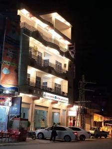 MingoraFR Darya E Swat Hotel的一个人在大楼前走过一辆白色汽车