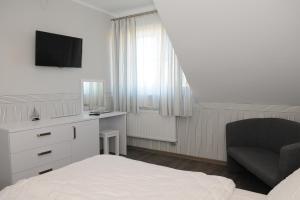 达洛科卡梅拉别墅旅馆的一间卧室配有一张床、一把椅子和电视