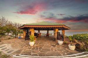 蒙巴萨PrideInn Flamingo Beach Resort & Spa Mombasa的毗邻大海的凉亭配有桌椅