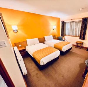特伦特河畔斯托克Tollgate Hotel & Leisure的两张床位于带黄色墙壁的酒店客房