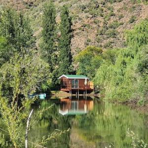 奥茨胡恩Old Mill Lodge, Seasonal Working Ostrich Farm & Restaurant, Oudtshoorn的河边的房子