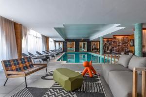 里蒙纽耶夏雷酒店的游泳池位于酒店客房内,配有沙发和橙色的图形