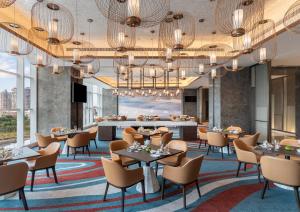 厦门厦门集美海景皇冠假日酒店（免费Mini Bar）的一间带桌椅的餐厅和一间酒吧