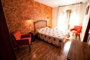 坎加斯-德奥尼斯Alojamiento Covadonga的一间卧室配有一张床和两张红色椅子