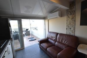 阿格德角Studio Naturiste CAPTIVE Héliopolis FG 13的一间带棕色真皮沙发的客厅和一个阳台