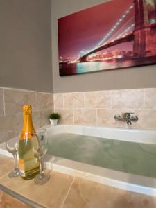 巴克乌Garsoniera Riviera的浴缸内的一瓶香槟和两杯酒