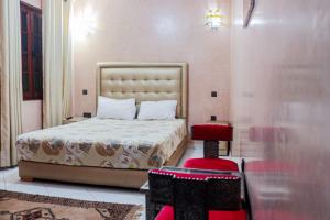 马拉喀什Riad Aymane的一间卧室配有一张床和红色凳子