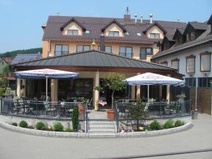 魏贝尔斯布伦Hotel Jägerhof的大楼前的餐厅,配有桌子和遮阳伞