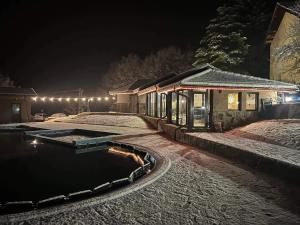 阿普里尔齐Хотелски комплекс САНЯ的一座房子,晚上在雪中设有游泳池