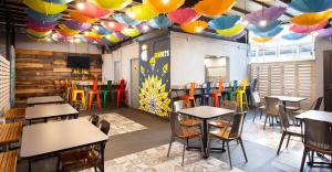 墨西哥城Hostal CASA MX centro的餐厅配有桌椅,并摆放着五颜六色的遮阳伞