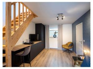 OverpeltB&B De Floreffe的客房设有楼梯和带电视的书桌。