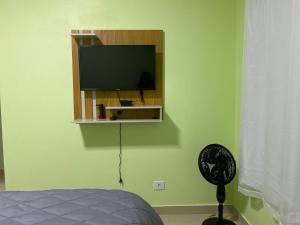 戈亚斯州上帕莱索Suítes Acolhedoras da Diva的一间位于绿色墙壁上并配有平面电视的卧室