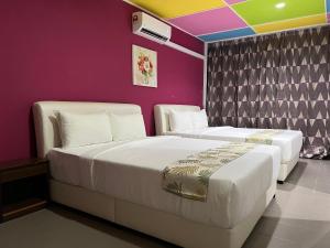 古晋Cassia Inn Kuching的紫色墙壁客房的两张床
