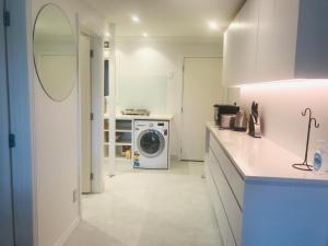 奥克兰海滩山林小屋公寓的白色的厨房配有洗衣机