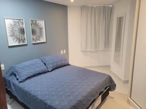 若昂佩索阿Espetacular Flat Miramar 3的卧室配有一张蓝色的床,墙上挂有两张照片