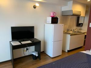 那霸Clean Hotels in Higashimachi的带冰箱的小厨房以及带微波炉的书桌。