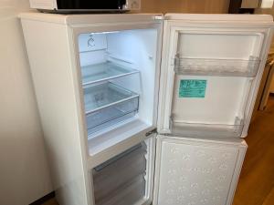那霸Clean Hotels in Higashimachi的厨房里空着冰箱,门开