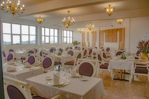 杜阿拉FAYA Hotel的宴会厅配有白色的桌椅和吊灯。