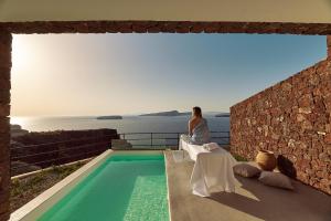 阿克罗蒂里Coco-Mat Hotel Santorini的坐在阳台上的女人,从阳台上望出大海