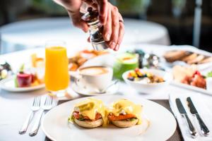 约翰内斯堡撒克逊Spa别墅酒店 的一张桌子,上面放着一盘早餐食品,还有人撒上酱汁