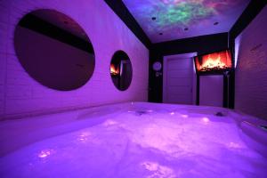 贝尔格莱德Aurora Lux Spa Smart apartments的浴室配有带紫色照明的大浴缸