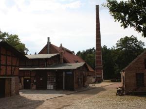 GlashütteFerienwohnung Am Roten Schloss的一座带高高的烟 ⁇ 和建筑物的旧谷仓