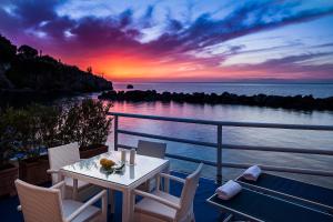 伊斯基亚伊斯基亚蓝光度假酒店的阳台的桌椅享有日落美景
