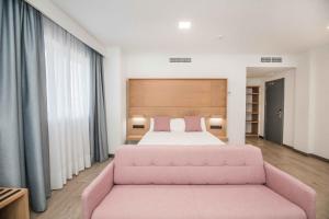 阿维拉Hotel Ciudad de Ávila的一间卧室配有粉红色的床和粉红色的沙发