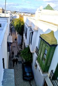 突尼斯Dar el médina的一条拥有白色建筑和绿色建筑的小巷