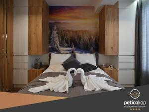 科帕奥尼克Apartman PETICA KOP A8 Kopaonik的两个白天鹅坐在床上