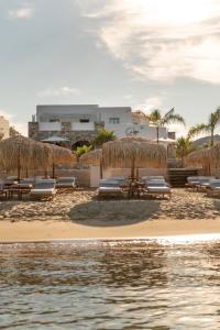波西多尼亚Calma Boutique Hotel的海滩旁设有长椅和遮阳伞