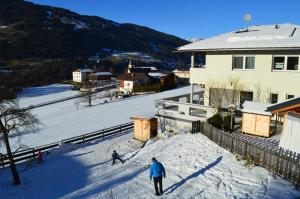 皮茨河谷阿兹尔Haus Raich - Pitztal Card im Sommer inklusive的两个人在房子附近的雪盖滑雪坡上滑雪
