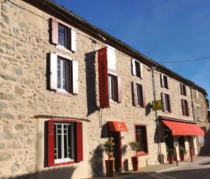 圣皮埃尔德日瓦Logis Hotel Restaurant LA BARGUILLERE的街上一座石制建筑,有红色百叶窗
