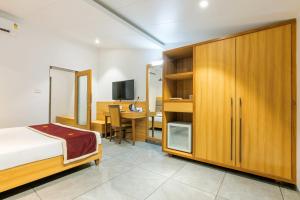 达曼Gold Beach Villa的一间卧室配有一张床和一张书桌及电视