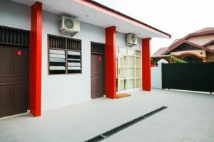 棉兰OYO 2940 Papakoel Guest House的车道上两排红色柱子的房子