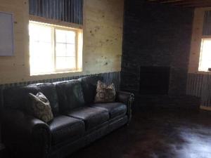 LewistownBig Horse Inn and Suites的壁炉间里的一张黑色皮沙发