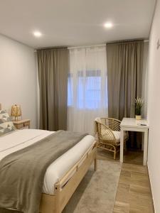 科维良Art'Estrela的一间卧室配有一张床、一张书桌和一个窗户。
