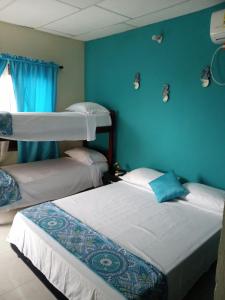 托卢AquaMarina Hostal的蓝色墙壁客房的两张床