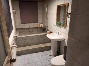 Wenquan九族飯店 臺東縣旅館004號的一间带水槽、浴缸和卫生间的浴室